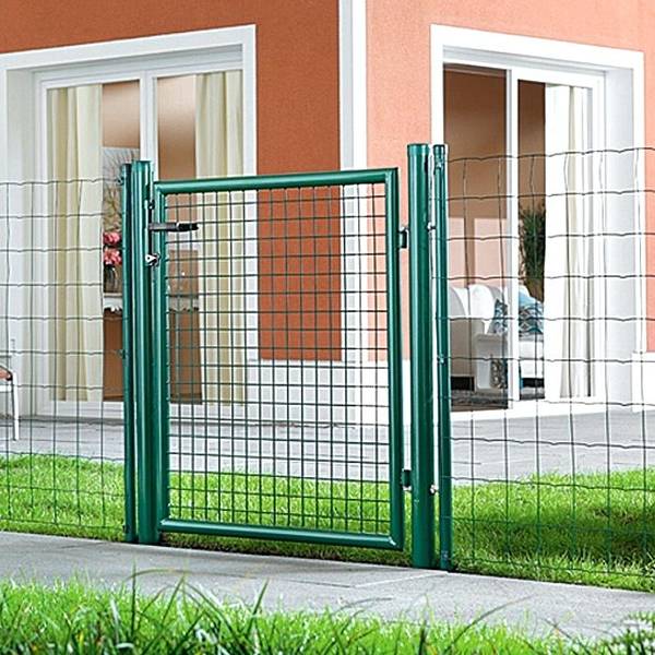 Green metal garden gate with round frame and post installed for grass entrance.