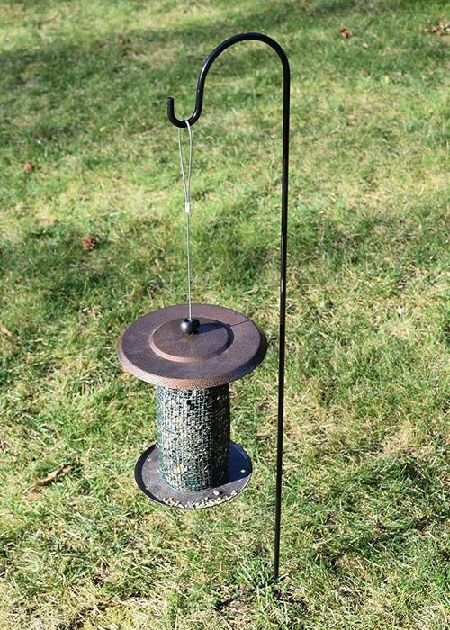 A bird feeder hanging on the single shepherd's hooks for birds.