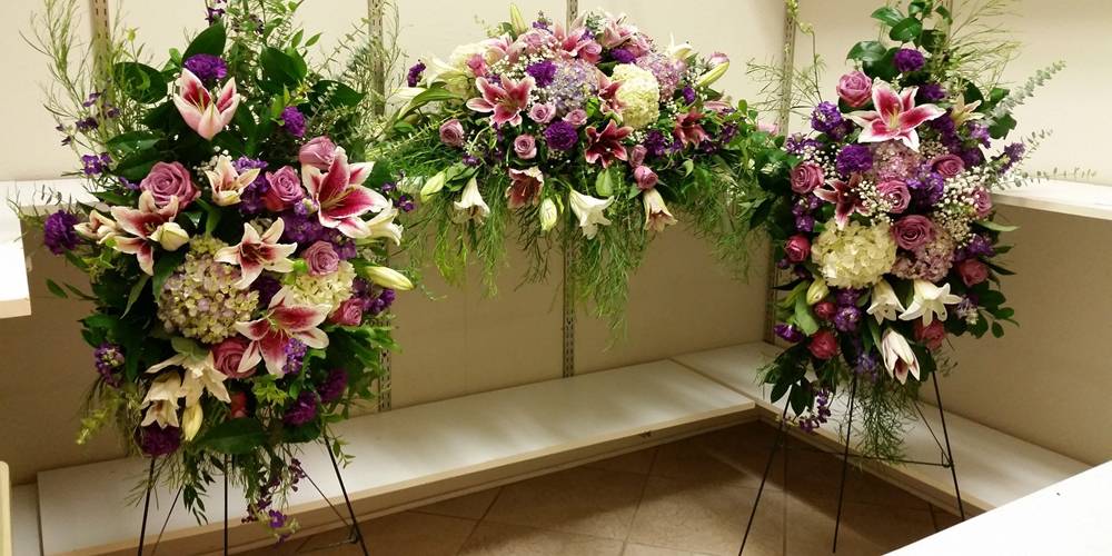 There are three funeral flowers supported with metal wire stands.