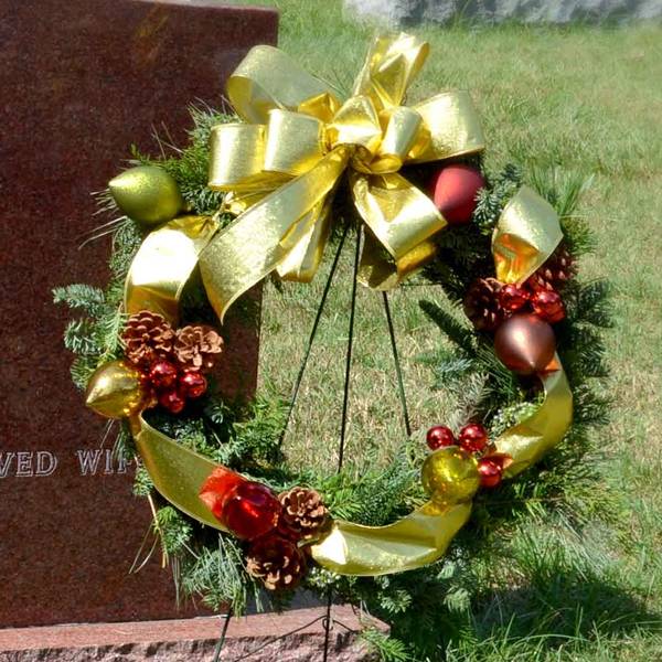 There is a round wreath with silk trim in the front of the grave.